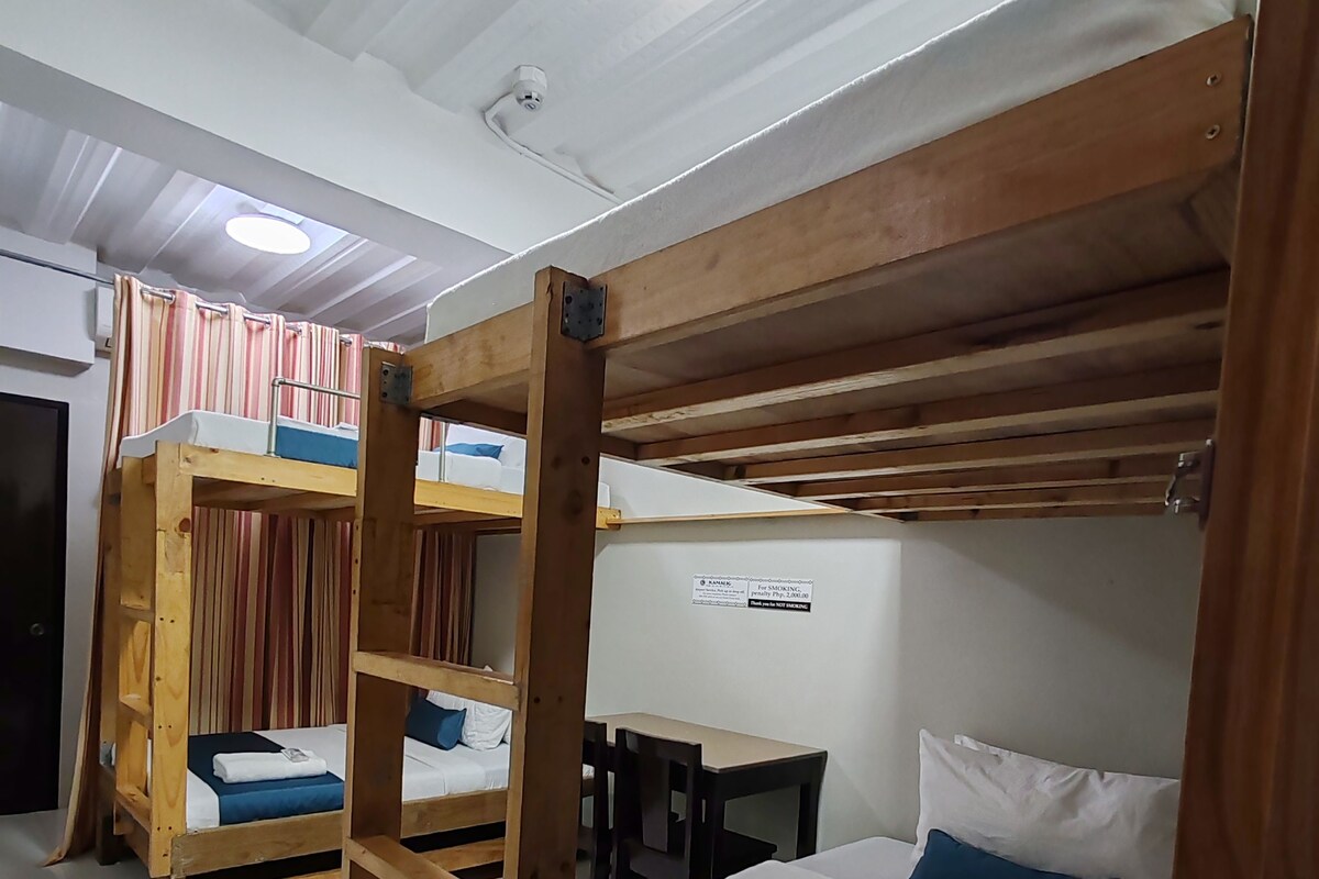A room with bunk beds, a desk, and a chair.