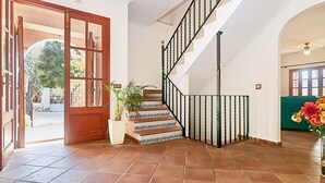 Una escalera con barandilla negra, una planta en maceta y una puerta que da al exterior.