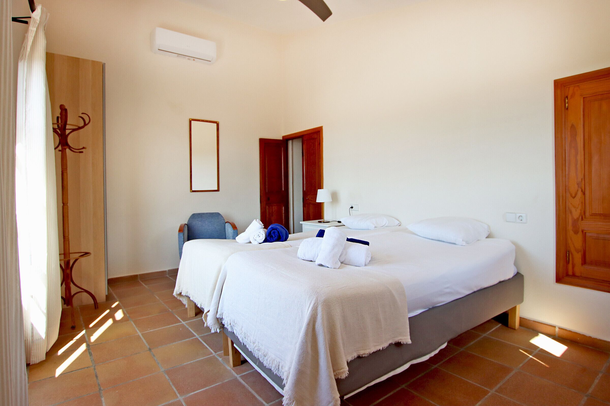 A hotel room with a bed, a chair, a table, and a door.