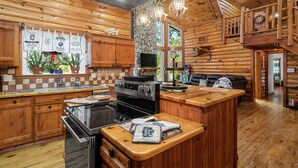 Interior de una cabaña de madera con cocina, comedor y habitación en altillo.