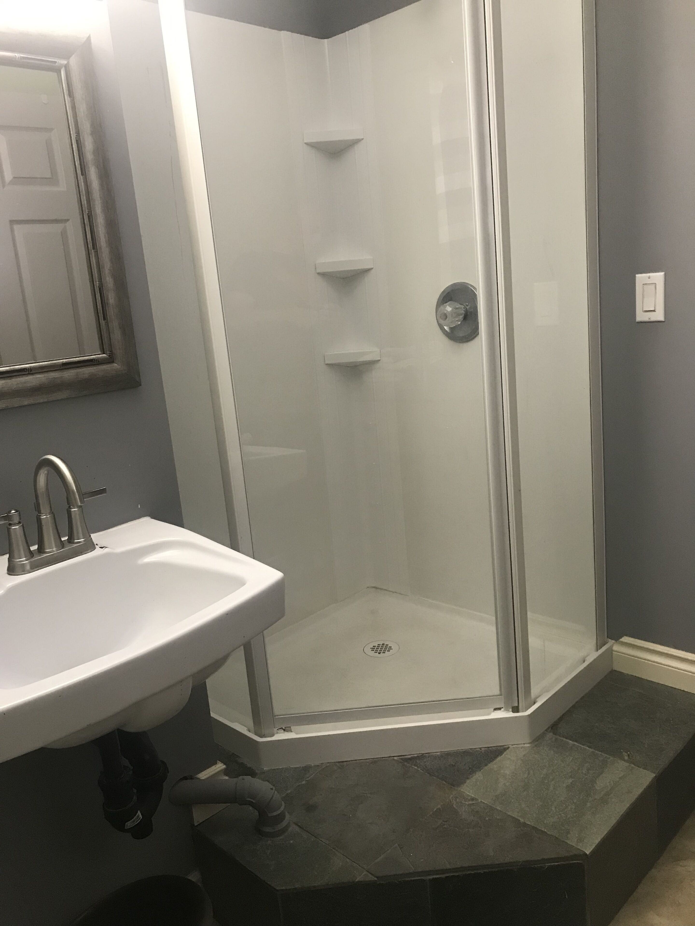 A bathroom with a glass-enclosed shower, a sink, and a mirror.