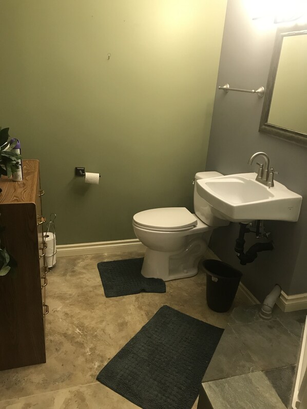 A bathroom with a toilet, sink, and a wooden cabinet.