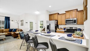 Een moderne keuken met houten kasten, roestvrijstalen apparatuur en een centraal eiland met barstoelen.
