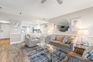 Een moderne woonkamer met een glazen salontafel, twee banken en een eethoek op de achtergrond.