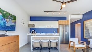 Eine moderne Küche mit Bar, Deckenventilator und einem großen Fernseher an der Wand.