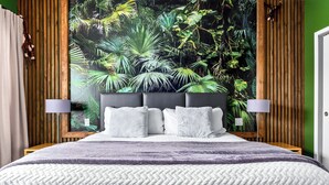 Ein Schlafzimmer mit einem großen Bett, zwei Nachttischlampen und tropischem Wandpapier.