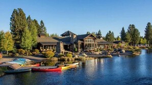 A lakeside lodge with a stone exterior, a dock with kayaks, and a clear view of the lake. - Sable Rock Retreat- Modern Luxury w/ 5 beds, 6 ba, spa, sauna, 2nd living room. (Bend)