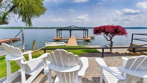 A lakeside deck with white Adirondack chairs, a wooden dock, and a gazebo. - Lakeview Heaven - Elegant Canandaigua Lake Getaway | Dock + Hot Tub (Canandaigua)
