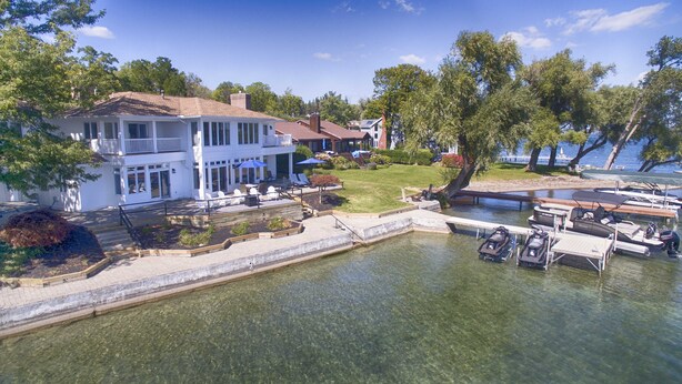A waterfront property with a large house, a dock with boats, and a grassy lawn. - Lakeview Heaven - Elegant Canandaigua Lake Getaway | Dock + Hot Tub (Canandaigua)
