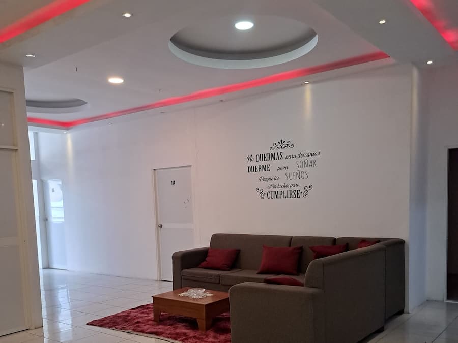 A modern living room with a sofa and a coffee table, a red rug, and a wall with motivational text.