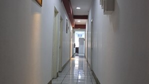 Un pasillo largo y estrecho con paredes blancas, piso de baldosas e iluminación empotrada.
