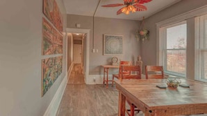 A dining area with a wooden table and chairs, a ceiling fan, and artwork on the walls. - Historic Riverfront Tropical Gem w/ River Views (Harrisburg)