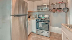 A compact kitchen with a stainless steel refrigerator, a microwave, and a stove. - Historic Riverfront Tropical Gem w/ River Views (Harrisburg)