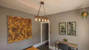 Une pièce décorée avec un grand tableau abstrait, un luminaire suspendu et deux tableaux encadrés accrochés au mur.