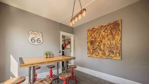 Un coin repas agrémenté d’un panneau Route 66, d’une table en bois, de tabourets rouges et d’un grand tableau abstrait accroché au mur.