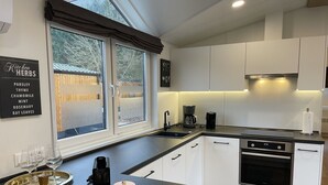 A modern kitchen with white cabinets, a black countertop, and a window with a view of trees.