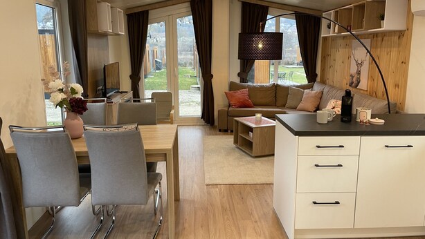 A modern interior with a dining area, sofa, and kitchenette.