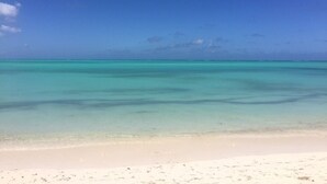 Une plage à l’eau turquoise et limpide, bordée d’un rivage de sable blanc.
