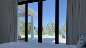 Une chambre dotée d’un grand lit, offrant une vue sur la plage, et d’une porte-fenêtre coulissante donnant sur un espace extérieur.