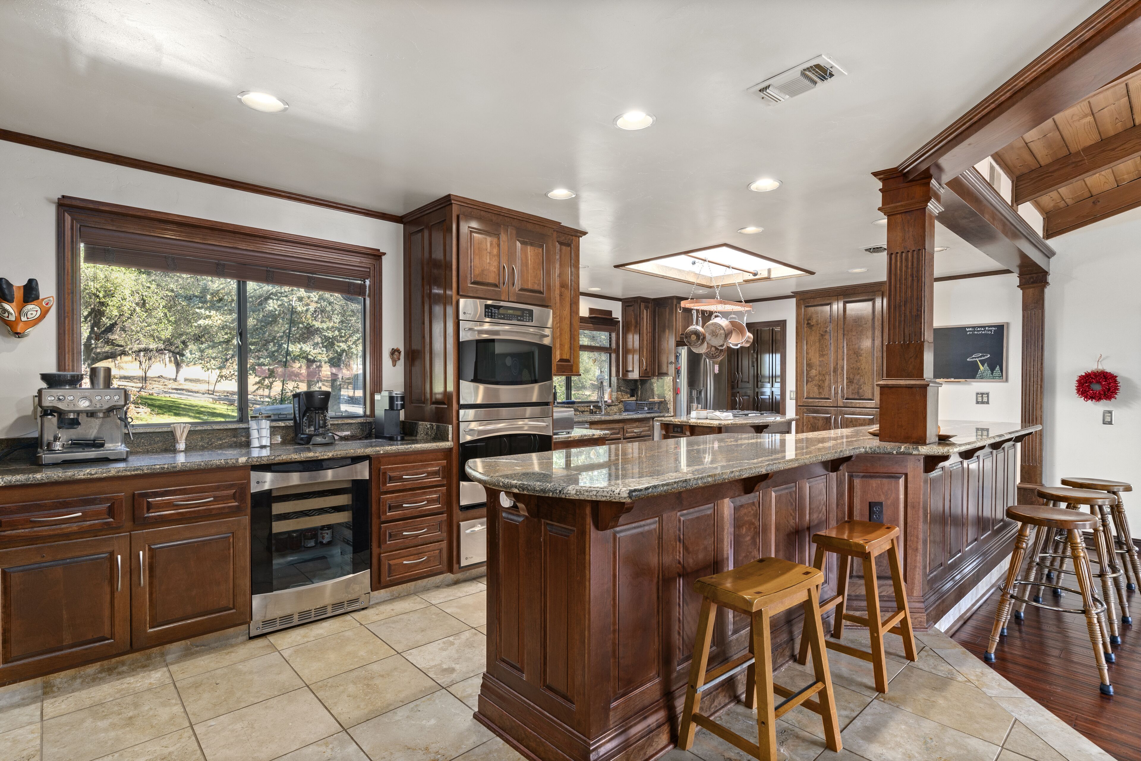 A spacious kitchen with wooden cabinets, stainless steel appliances, and a large island with stools.