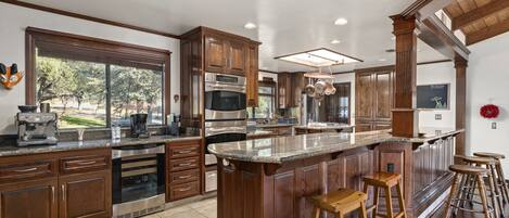A spacious kitchen with wooden cabinets, stainless steel appliances, and a large island with stools.