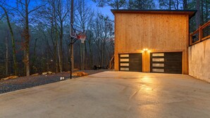 Une cabane moderne en bois, avec une allée en béton et un panier de basketball.