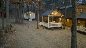 Eine Hütte mit Veranda und Terrasse, umgeben von Bäumen.