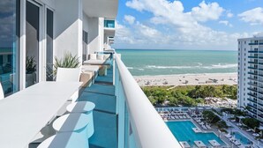 Ein Balkon mit Meerblick und ein Poolbereich mit Liegestühlen.