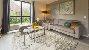 A living room with a sofa, a coffee table, a lamp, and a large window with curtains.