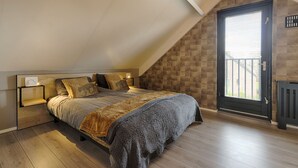 A bedroom with a sloped ceiling, a bed with a wooden headboard, a nightstand, and a window with blinds.