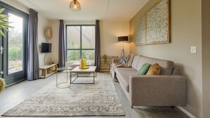 A modern living room with a sofa, a coffee table, a floor lamp, and a large window.