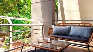 A glass-top table with two glasses, a wicker sofa with cushions, and a metal railing. - Modern 2BR/2BA Condo w| Proximity to Beach & Town - Casa Blanca 6 (Potrero)