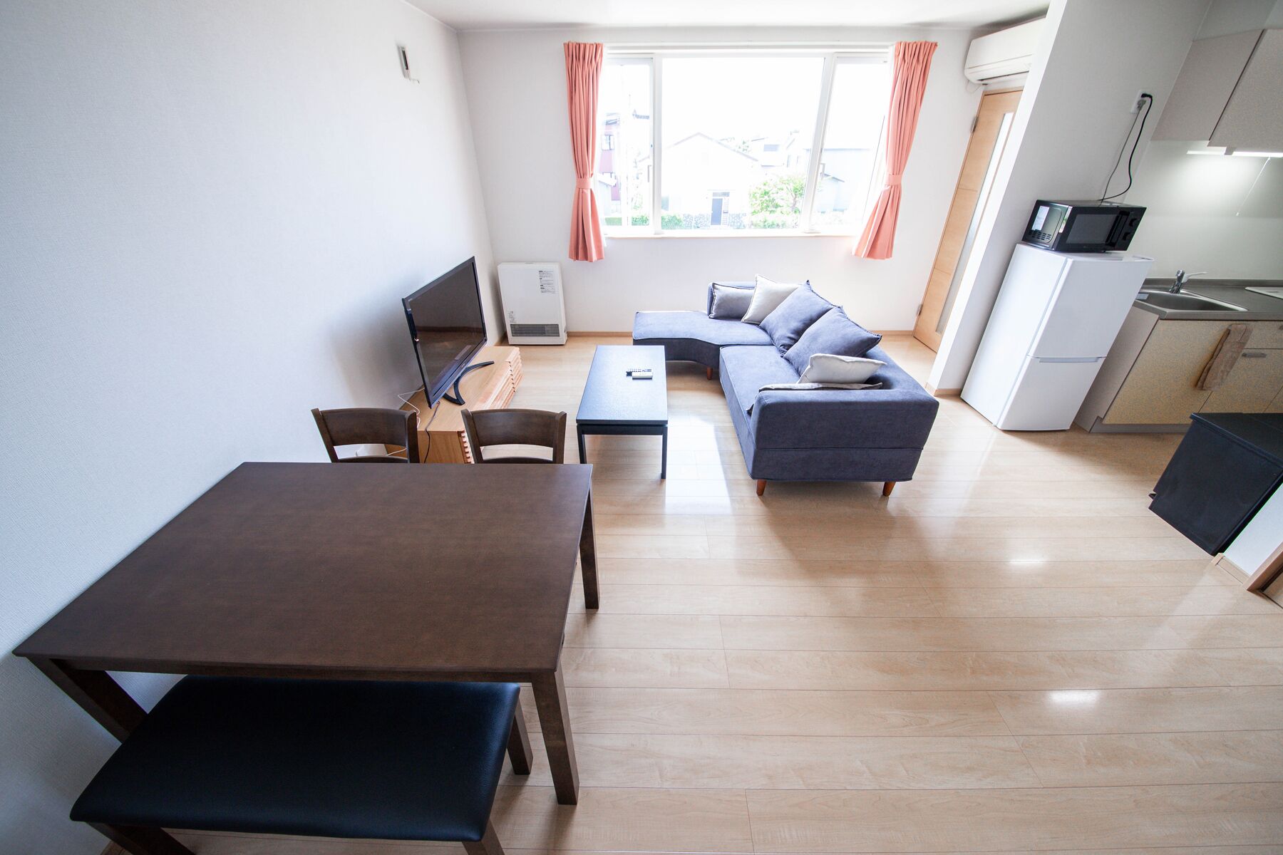 A modern living room with a sofa, a dining table, and a TV.