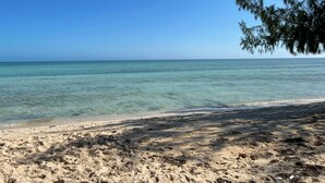 Uma praia com águas turquesa cristalinas e areal arenoso.