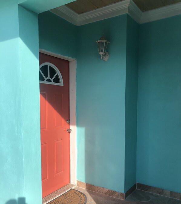 A red door with a white trim and a small white lantern above it. - Three A's Getaway, 15 min walk to sun, sand and sea! (Nassau)
