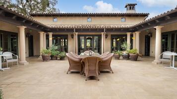 A courtyard with a central dining area featuring wicker furniture and potted plants.