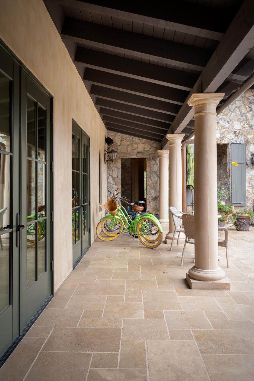 A covered outdoor area with stone walls, a green bicycle, and a table with chairs.