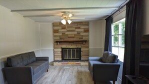 A living room with two sofas, a fireplace, and a ceiling fan. - Riverfront Home (Tidioute)