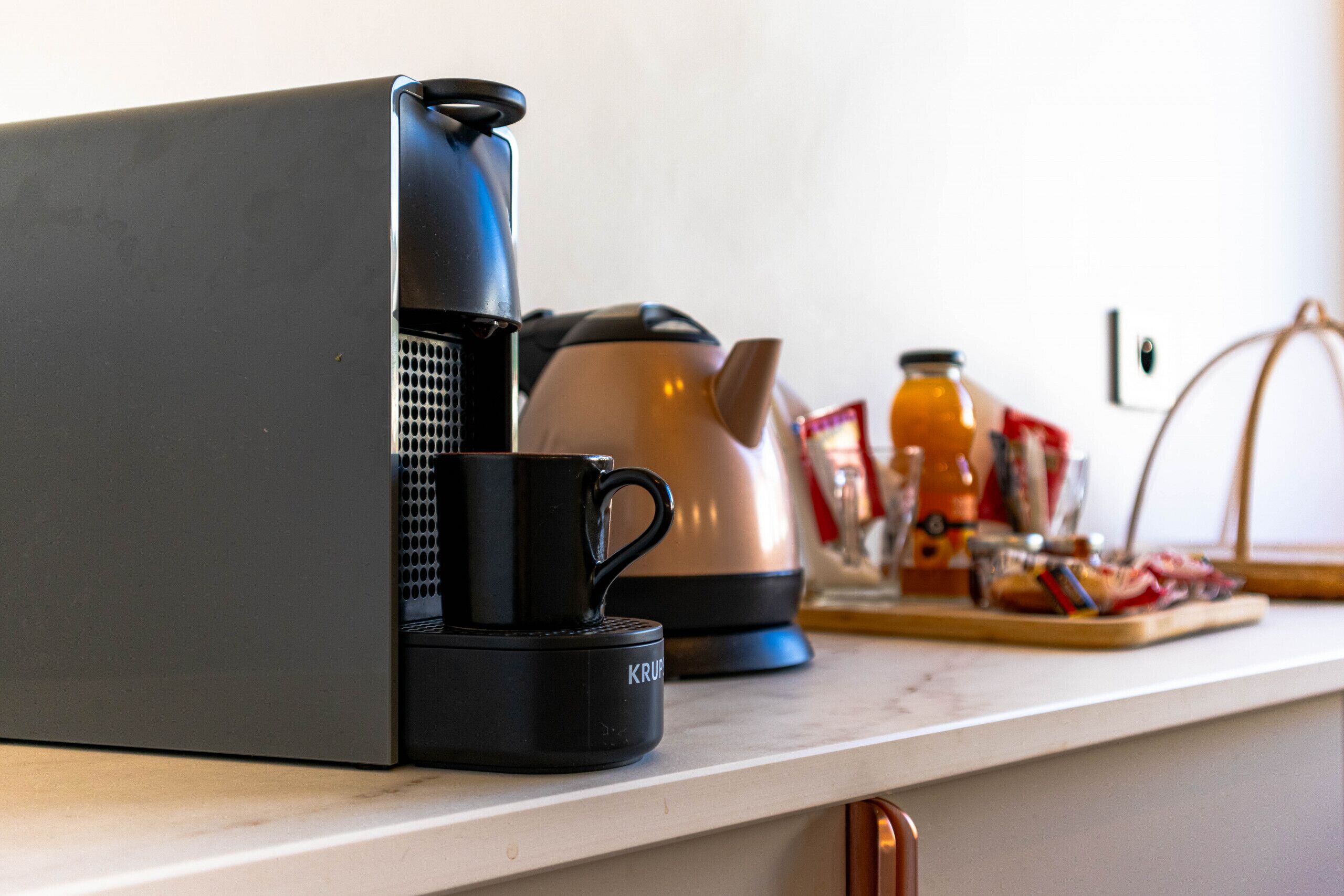 Eine Küchenarbeitsplatte mit Kaffeemaschine, Wasserkocher und einer Platte mit Lebensmitteln.