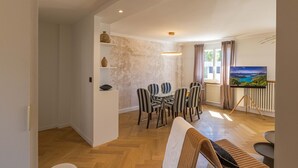 Een ruime woonkamer met een eethoek, een bank en een televisie op een standaard.