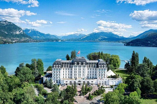 Situated by a serene lake, this historic hotel offers a classic European architectural style with a symmetrical facade and central tower.