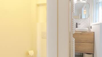 Une petite salle de bain comprenant des toilettes, un lavabo avec un miroir et un espace douche.