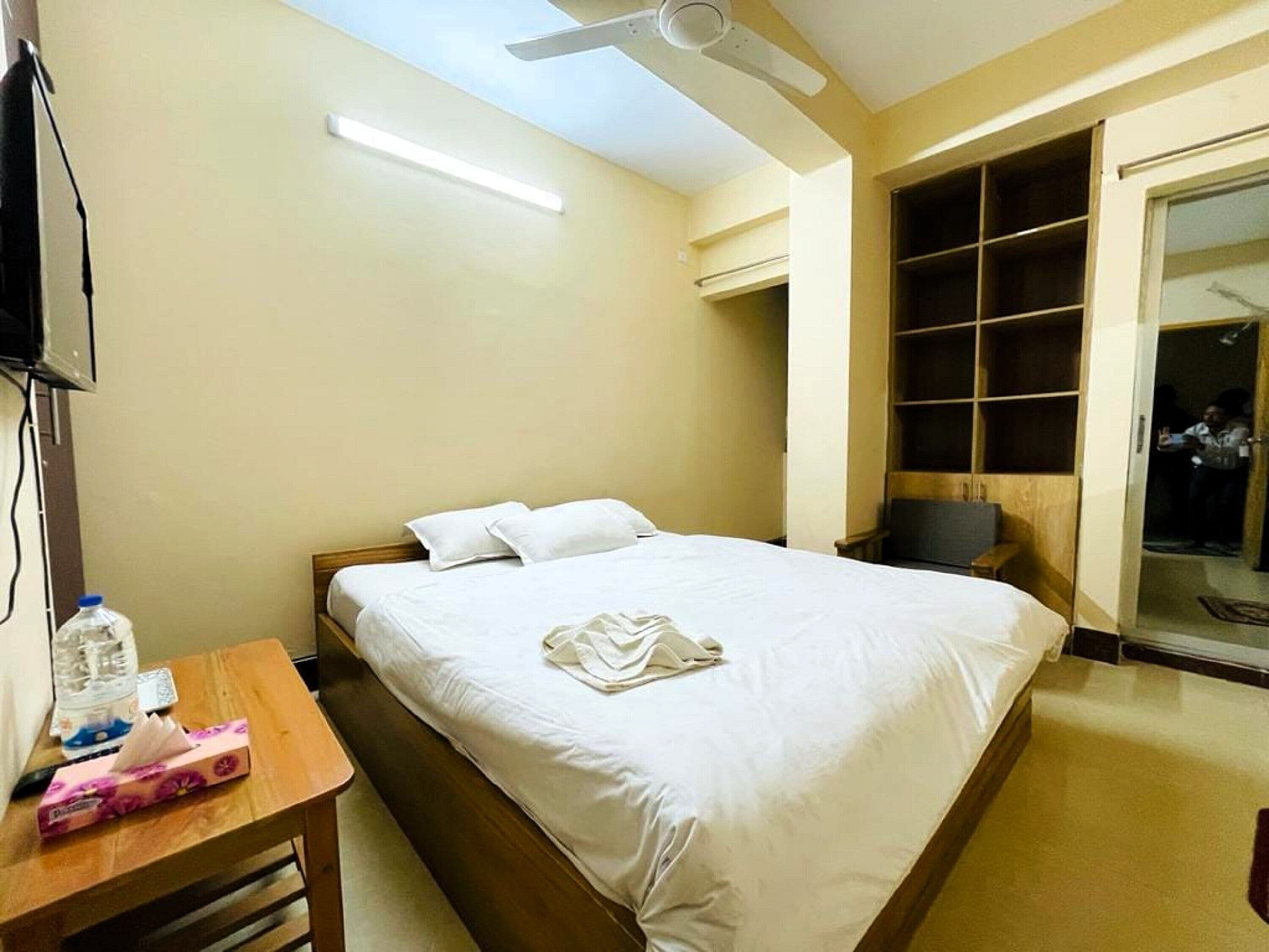 Una habitación de hotel con cama, mesita de noche y armario.