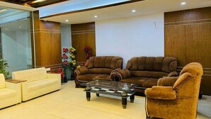 A modern lobby with two brown sofas, a white sofa, and a glass coffee table. - Reem Resort (Cox's Bazar)