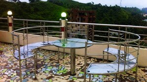 A rooftop terrace with a mosaic floor, metal railings, and a glass table. - Reem Resort (Cox's Bazar)
