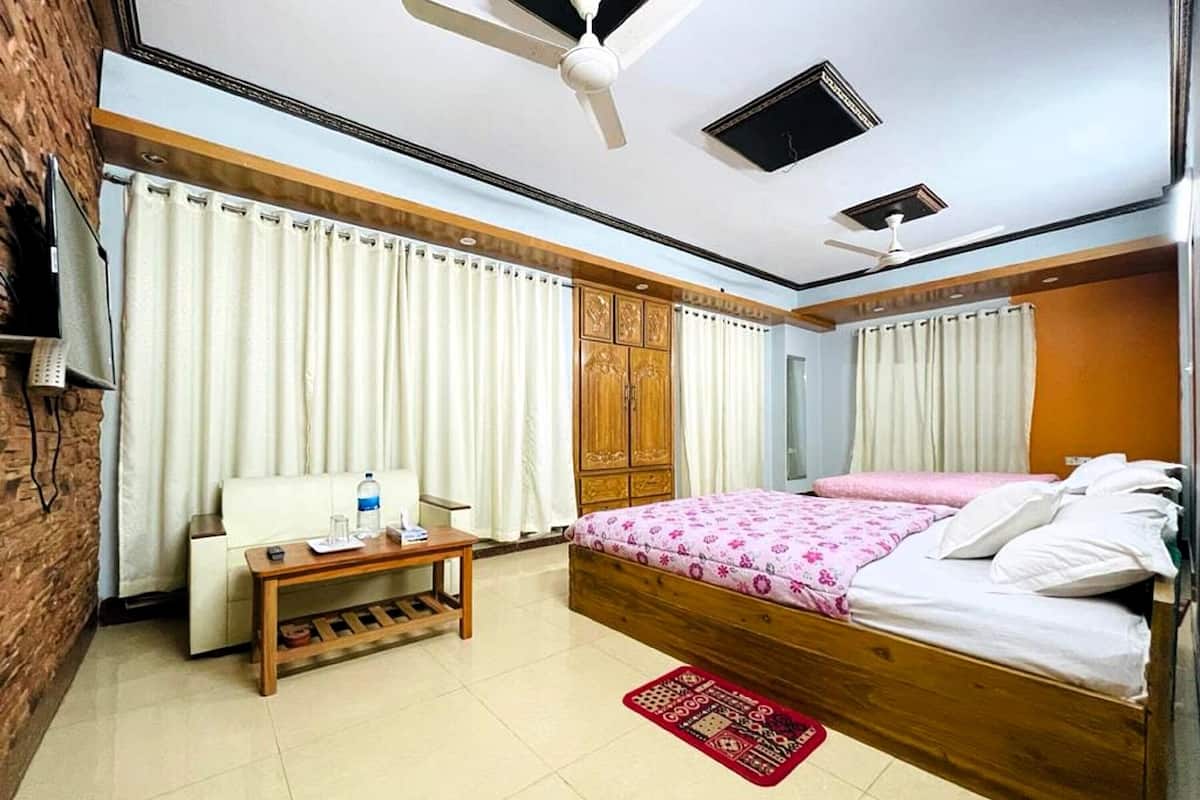 Ein Hotelzimmer mit Bett, Holzschrank, kleinem Tisch, Stuhl und Fernseher.