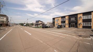 A street with buildings, including a two-story structure with a sign reading "Mei-Izon".