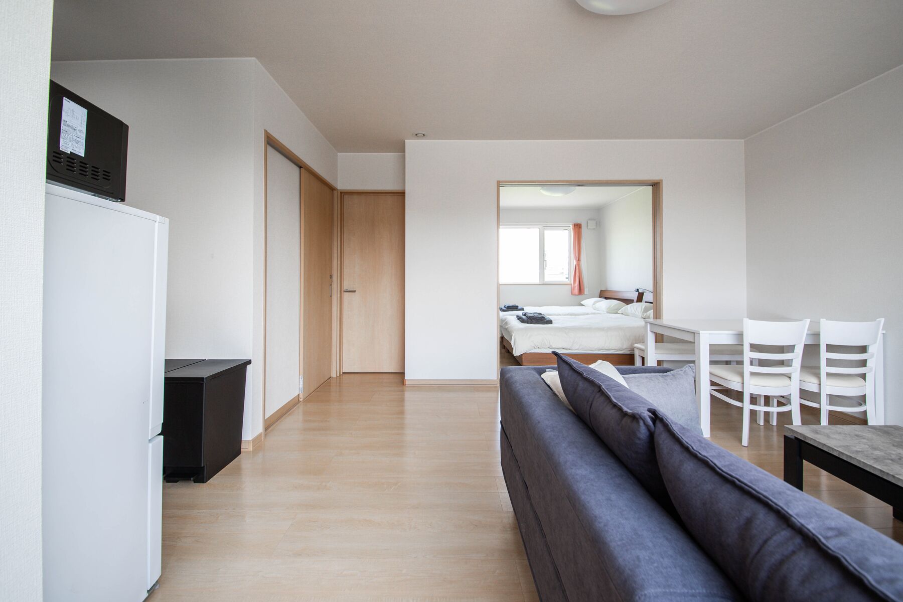 A modern, minimalist hotel room with a sofa, a dining table, and a bed.