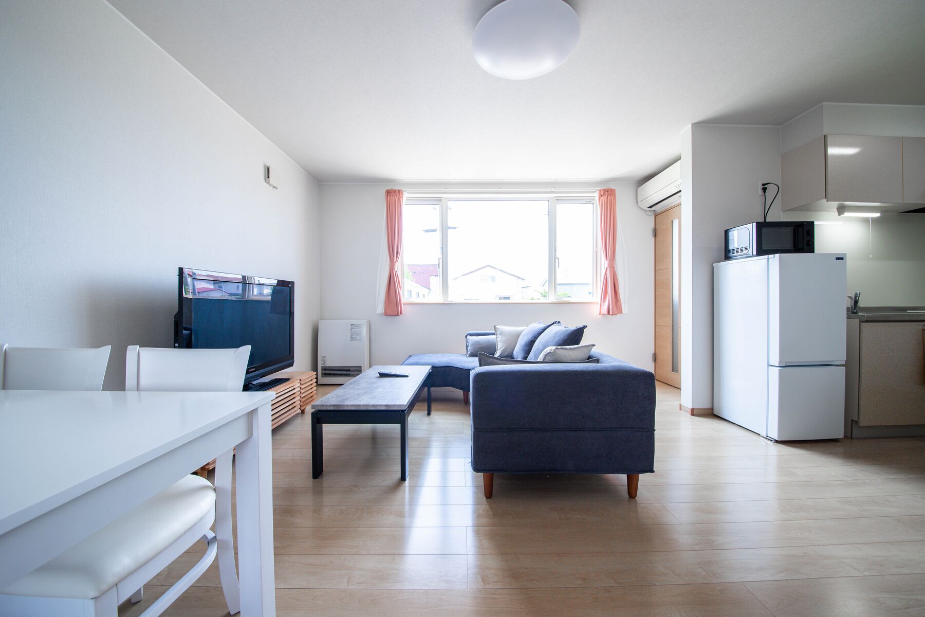 A modern apartment with a living room, dining area, and kitchen.