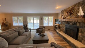 Ein Wohnzimmer mit Kamin aus Stein, einem großen Sofa und einem Fernseher.